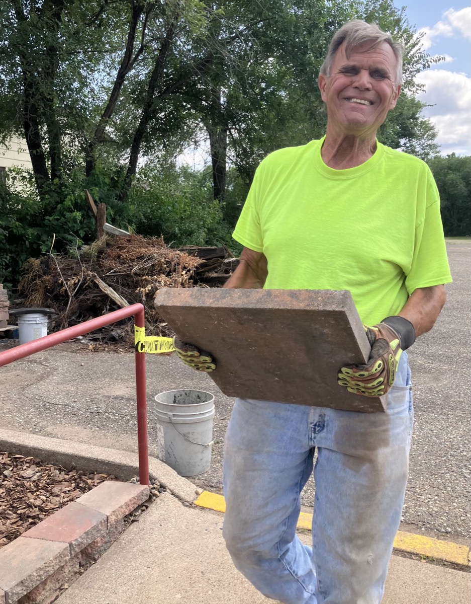 Don Steiskal carrying a paving stone while working on the church parking lot landscape